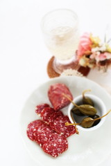 Italian sausage Salami sliced on dish with caper berry