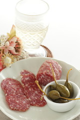 Italian sausage Salami sliced on dish with caper berry