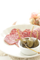 Italian sausage Salami sliced on dish with caper berry