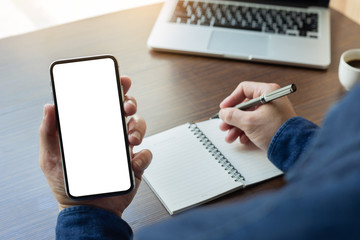 Mockup image blank white screen cell phone.man hand holding texting using mobile on desk at office.background empty space for advertise text.people contact marketing business,technology 