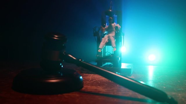 Death penalty electric chair miniature on dark. Creative artwork decoration. Image of an electric chair scale model on a dark backgorund