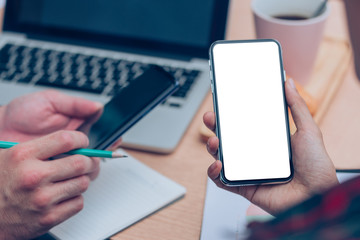 Mockup image blank white screen cell phone.man hand holding texting using mobile on desk at office.background empty space for advertise text.people contact marketing business,technology 