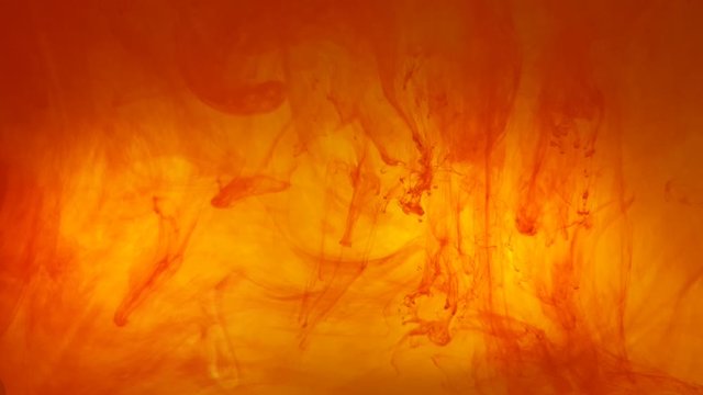 Ink swirls creating a fire burning effect with orange and red dye moving in the water, beautiful background color footage.