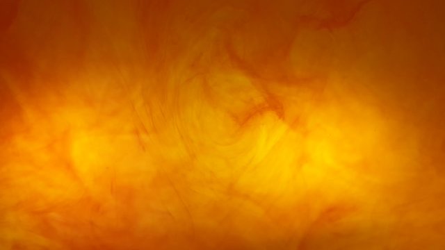 Ink swirls creating a fire burning effect with orange and red dye moving in the water, beautiful background color footage.