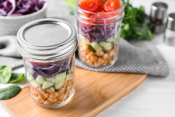 Healthy salad in glass jars on white table
