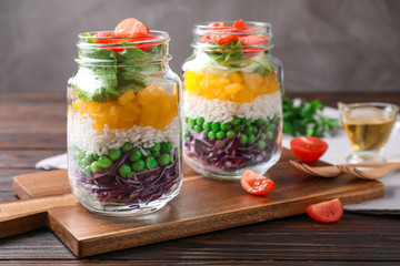 Fototapeta na wymiar Healthy salad in glass jars on wooden table