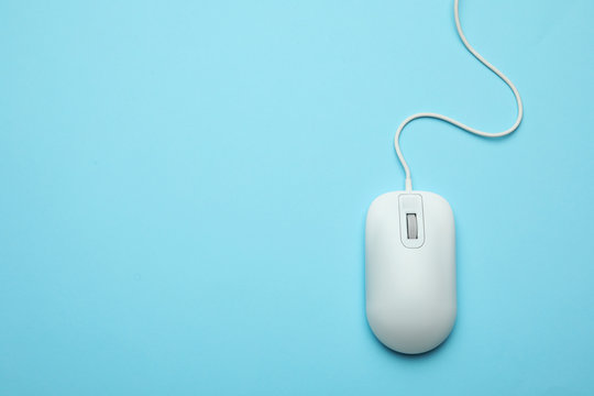 Wired computer mouse on light blue background, top view. Space for text