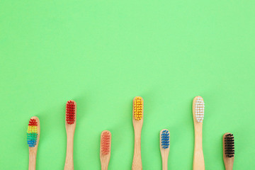Natural toothbrushes made with bamboo on green background, flat lay. Space for text
