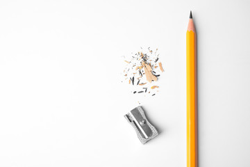 Pencil, sharpener and shavings on white background, top view