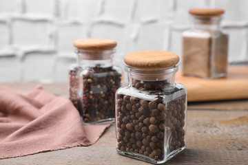 Glass jars with peppercorns on wooden table
