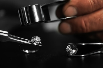 Professional jeweler working with beautiful ring at table, closeup