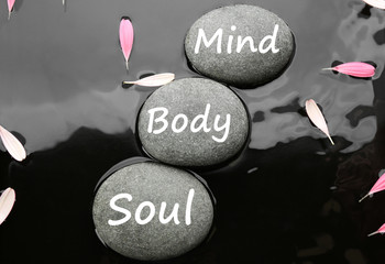 Spa stones with words Mind, Body, Soul and pink flower petals in water, flat lay. Zen lifestyle
