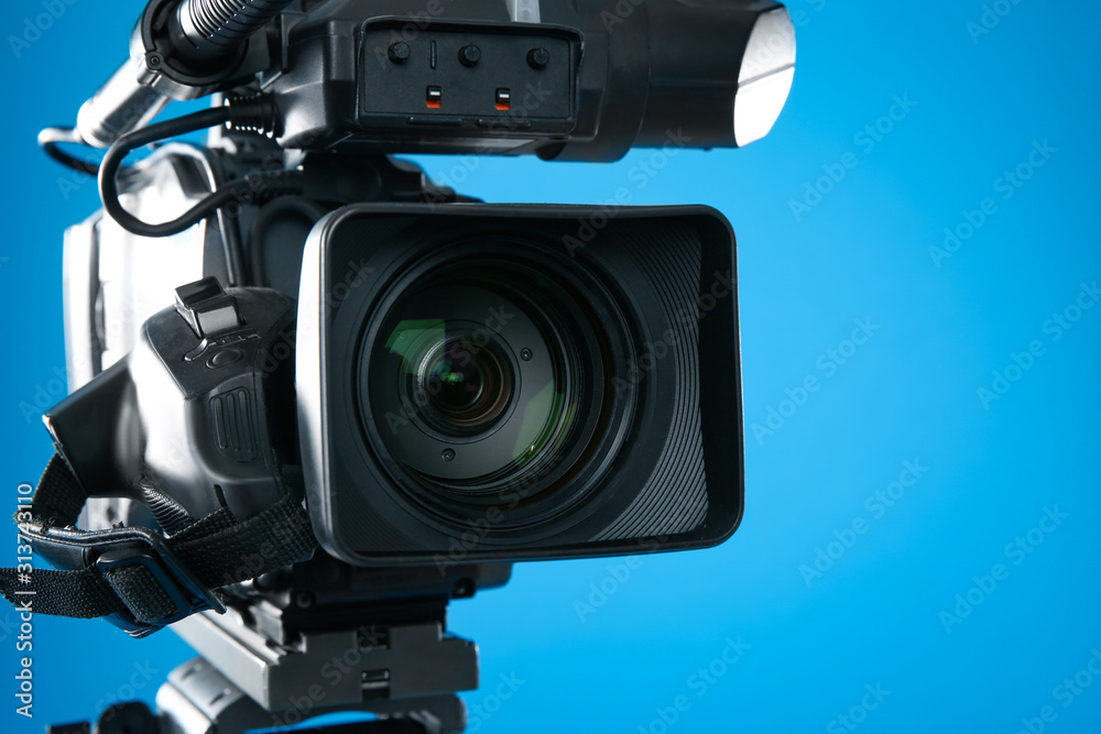 Wall mural professional video camera on blue background, closeup