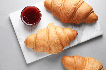 Tasty fresh croissants and jam on grey table, flat lay