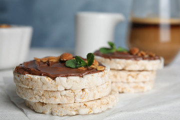 Puffed rice cakes with chocolate spread on white wooden table, closeup