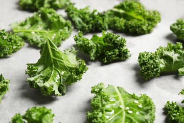Raw cabbage leaves on parchment paper, closeup. Preparing kale chips