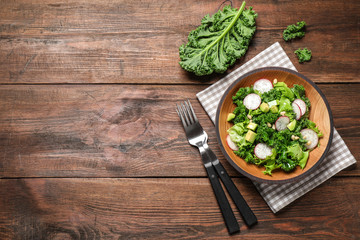 Delicious kale salad on wooden table, flat lay. Space for text
