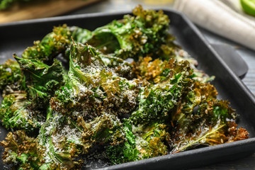 Tasty baked kale chips with cheese on table, closeup