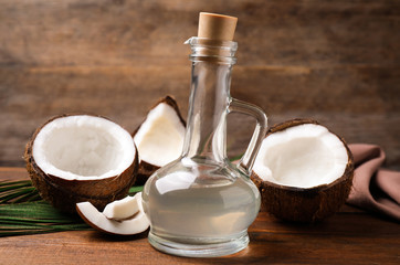 Fototapeta na wymiar Coconut oil in glass jug on wooden table