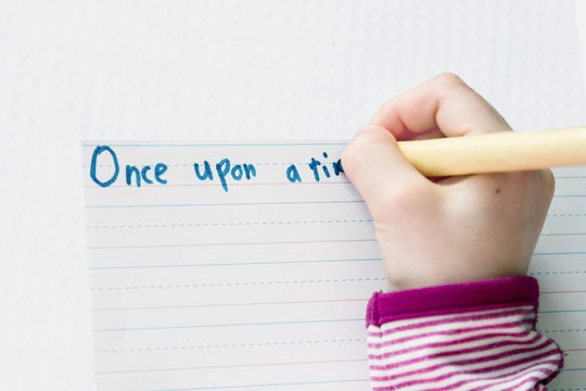 Child begins a story with Once upon a time; Child starts a story and prints with a pen