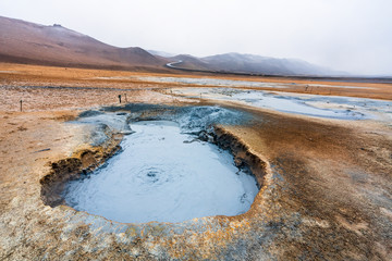 Bubbling geothermal hot/mud pool in the Hverarond area near Myvatn in the Icelandic landscape. Colorful and textured volcanic mineral rich sulphur ground infront.