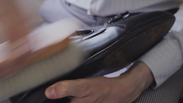 Close-up of a young Caucasian man repairing an old male leather shoe.