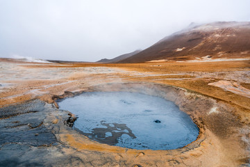 Bubbling geothermal hot/mud pool in the Hverarond area near Myvatn in the Icelandic landscape. Colorful and textured volcanic mineral rich sulphur ground infront.