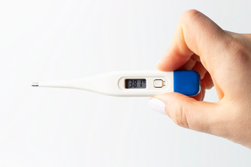 Female hand holds a thermometer to measure temperature on white background.