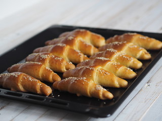 Ready-made toasted homemade bagels on a black baking sheet from the oven. Ready to eat. Sprinkled with sesame seeds. Home kitchen.