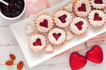 Valentines Day jam cookies with heart shapes. Above view on a serving plate against a white wood...