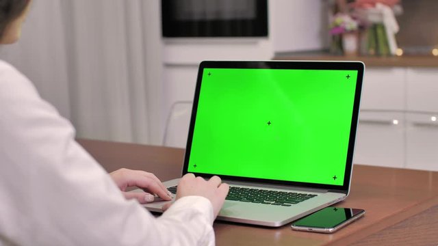 Woman using laptop computer with laptop green screen, 4K shot. Technology, chroma key, template, mockup and entertainment concept.