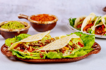 Meat, lettuce, tomato and cheese in soft tortillas. Mexican cuisine.