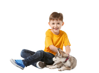 Little boy with cute husky puppy on white background