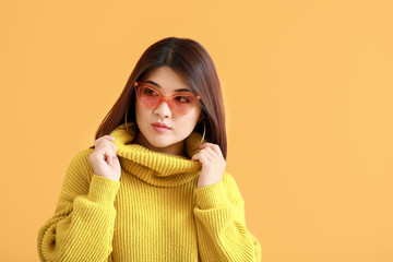 Portrait of beautiful young Asian woman on color background