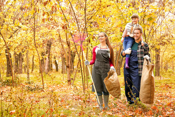 Naklejka premium Family cleaning up autumn leaves outdoors