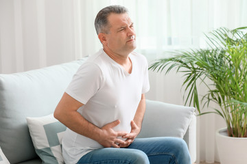 Mature man suffering from abdominal pain at home