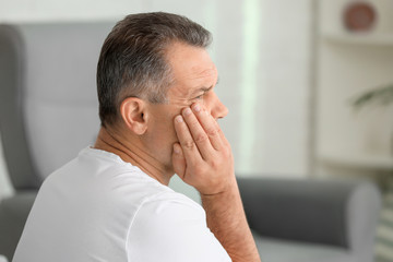 Mature man suffering from tooth pain at home