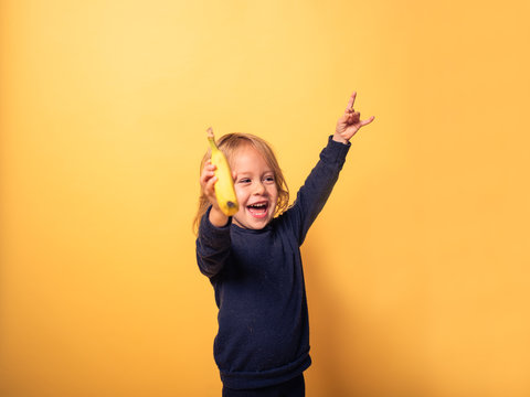Heavy metal toddler with banana against yellow background