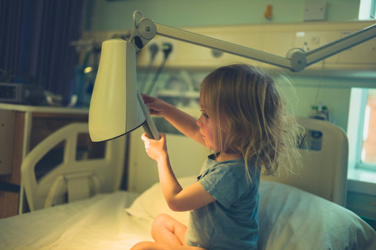 Little toddler in hospital bed with a lamp
