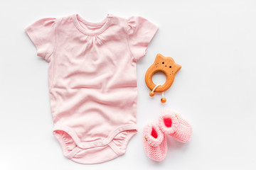 Pink bodysuit for baby girl near children's things on white background top-down