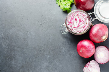Pickled chopped red onion in vinegar in a glass jar. A delicious side dish for meat and fish dishes. Light grey background.