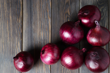 Lots of red onions on a brown wooden background. Red onions on old crumpled burlap. Copy space