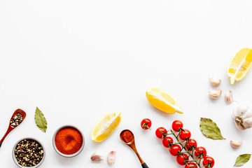 Cooking background with spices, vegetables - pepper, garlic, cherry tomatoes - on white desk top-down frame copy space