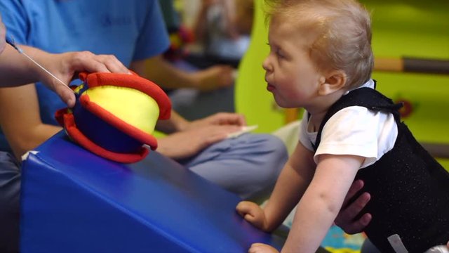 Little child with cerebral palsy on physiotherapy in a children therapy center. Boy with disability has therapy by doing exercises with physiotherapists. Little child in rehabitation centre