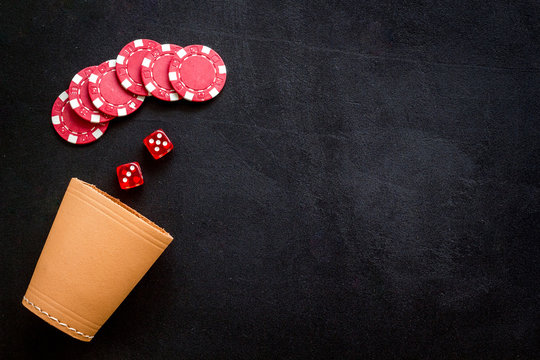 Poker hazard game concept. Chips, dices, cup for dice on black background top-down copy space