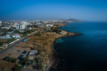 Aerial view of Dakar, looking from Ngor towards the African Renaissance Monument which is seen in the far background. Beach and a bar is seen in the front.