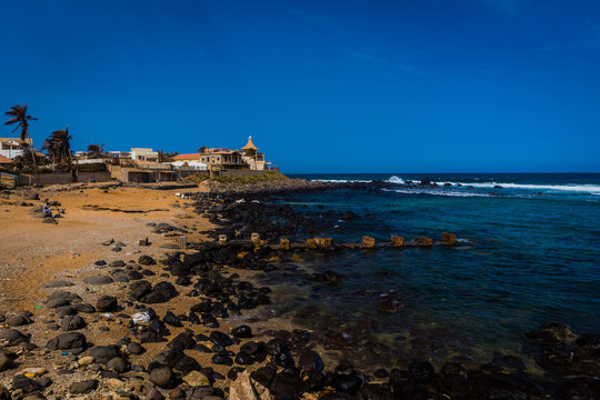 Beach with blue water and rocky and sandy coast on the suburb of Tonghor in Dakar, Senegal. African beach in Dakar on a sunny day.