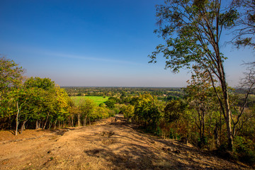 The blurry nature background of the Wat Saphan Hin walkway has long, stone bridges on a hill, with tourists coming to see the beauty in Sukhothai, Thailand.
