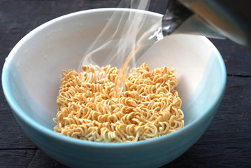 Pouring hot water to instant noodle in cup.