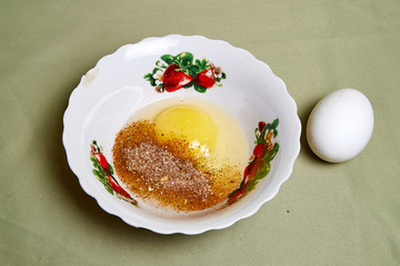 Raw egg on a white plate on the table. Cooking eggs for cooking